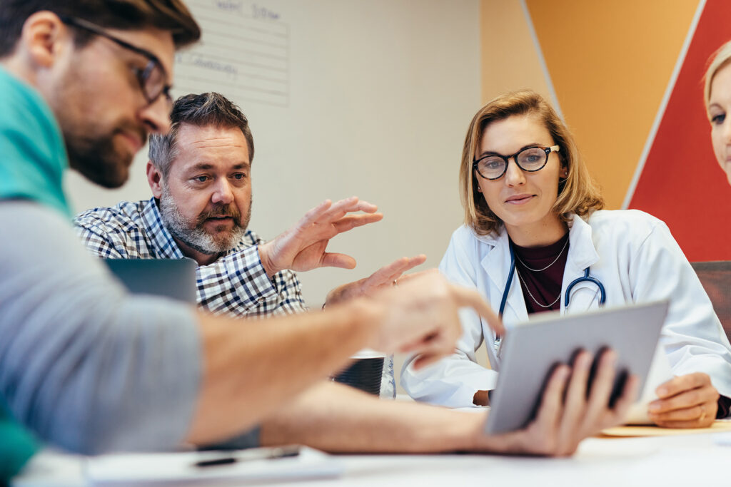 Doctor and medical professionals reviewing data over a tablet